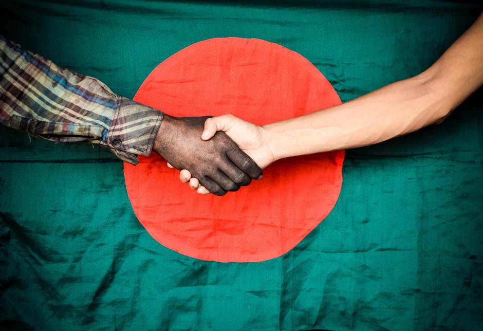 Two hands shaking in front of the Bangladesh flag, symbolizing unity and cooperation.